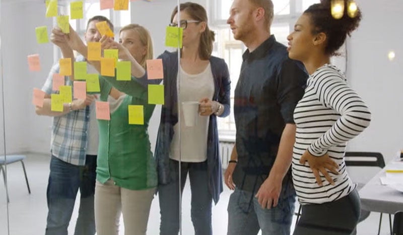 A team brainstorming ideas using sticky notes on a glass wall.
