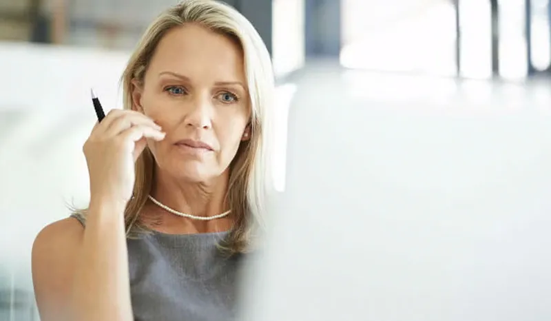 A woman deep in thought while working at her desk in the office.